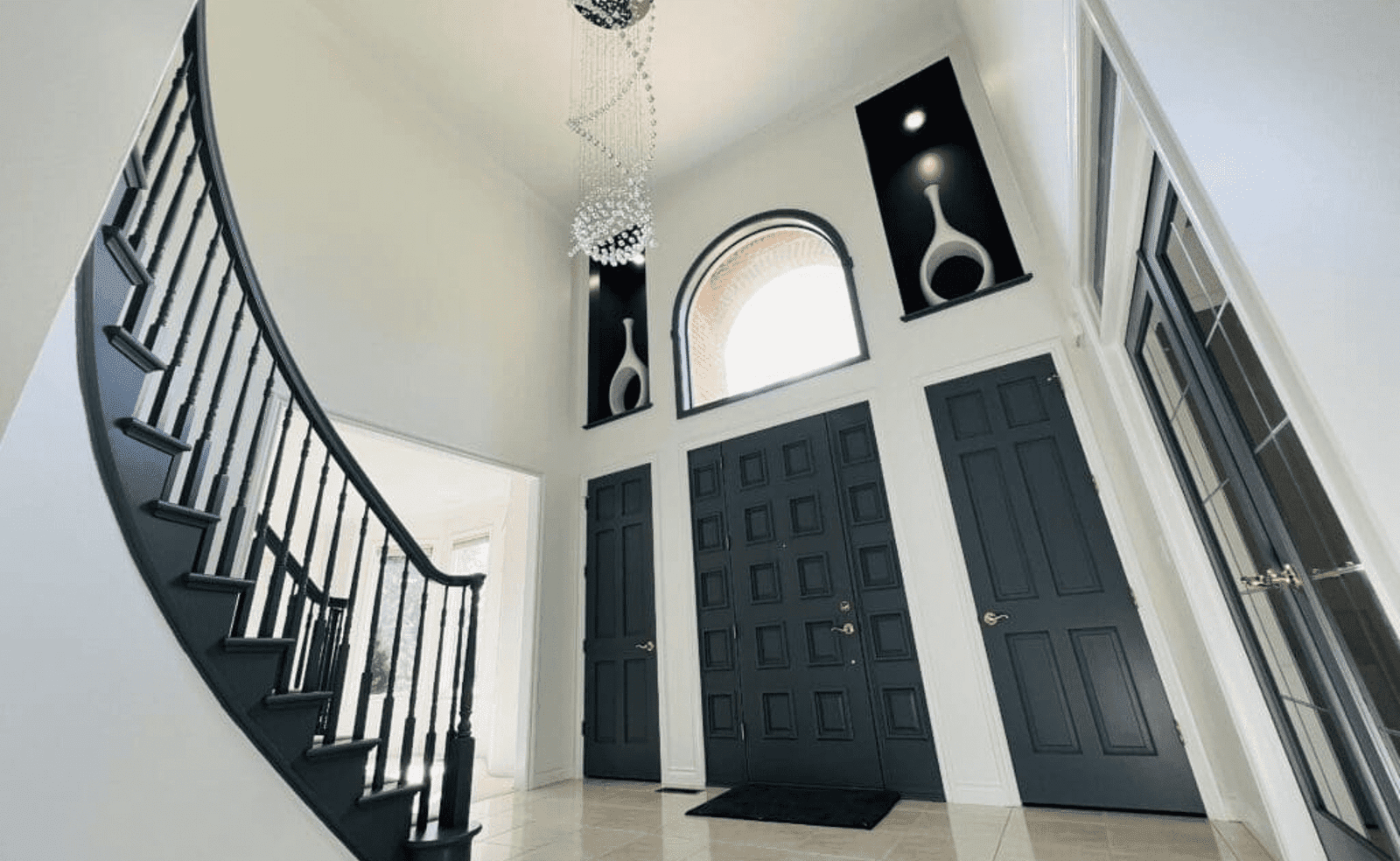 Sterling Heights, MI 9 Spacious foyer with dark staircase, double doors, chandelier, art niches, and arched window.