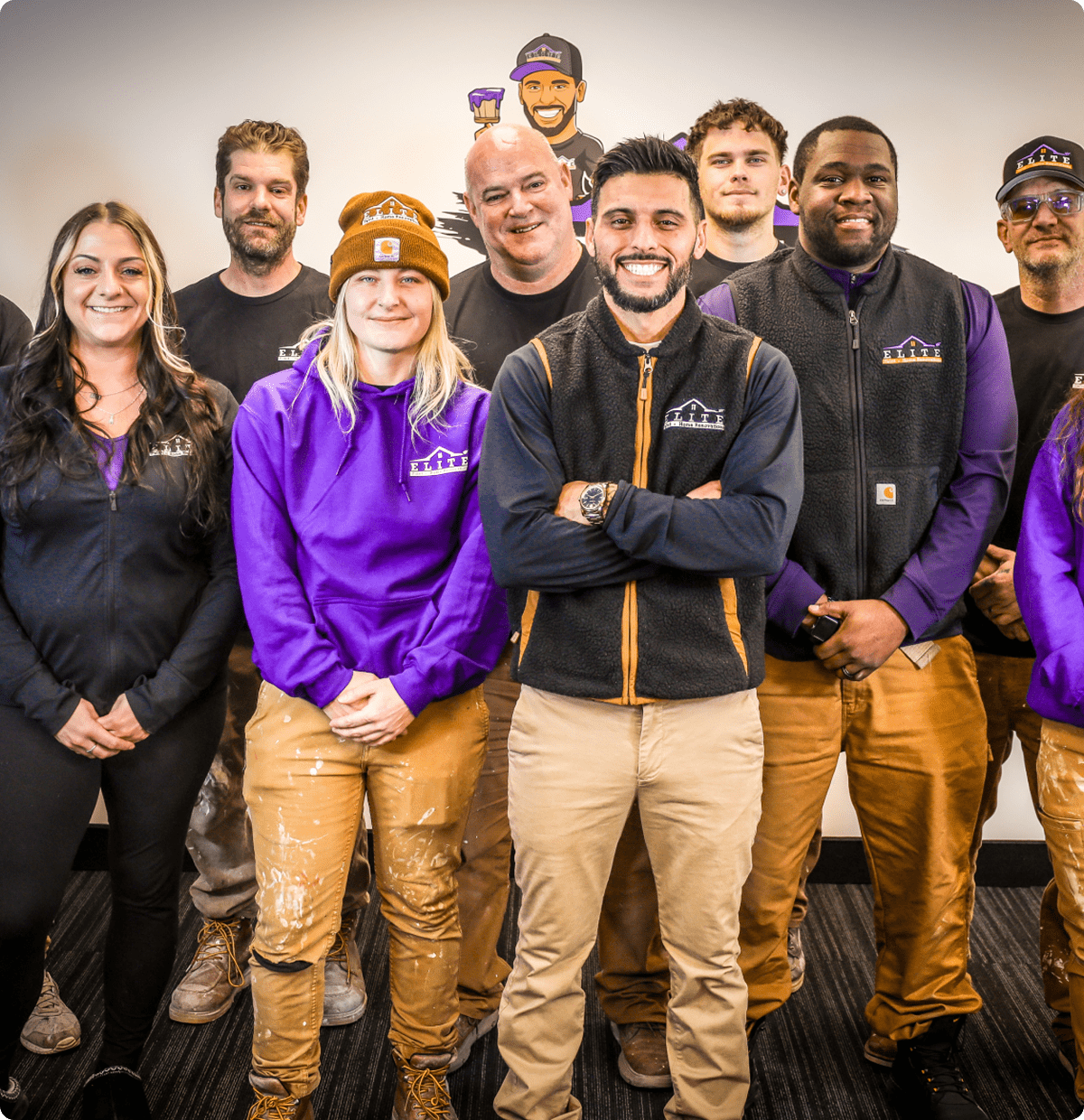 Sterling Heights, MI 17 Nine people in matching work uniforms stand together by a wall with a logo.